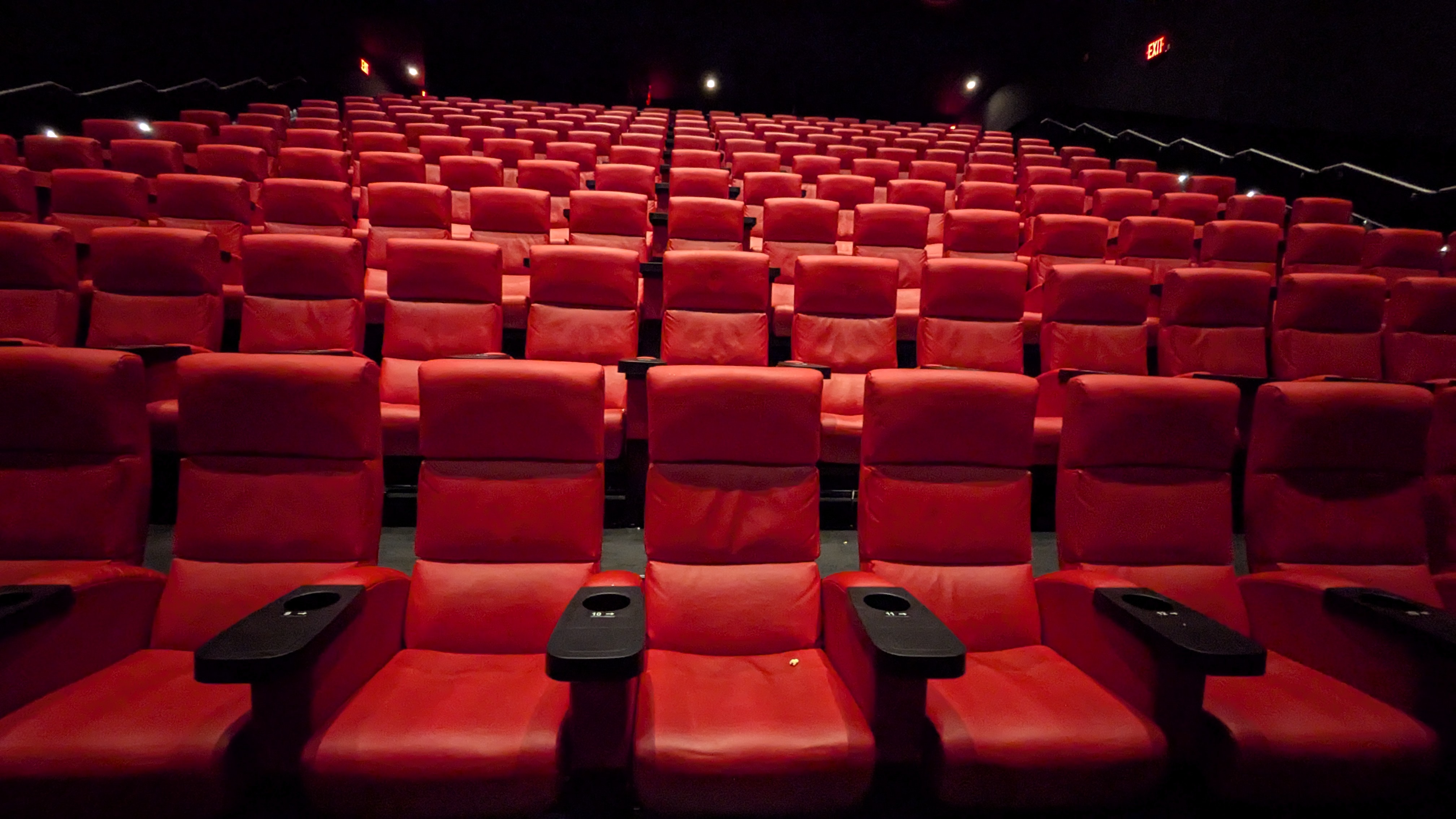 Rows of cinema seats inside a darkened movie theater.