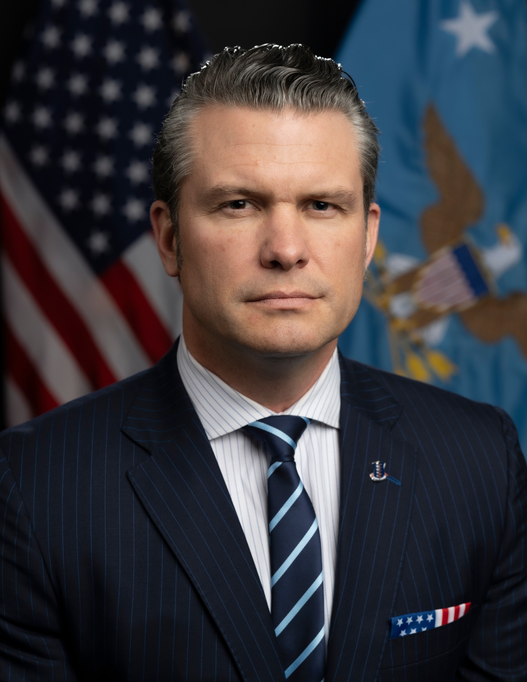 Pete Hegseth in his January 2025 official portrait, wearing a dark suit in front of flags.