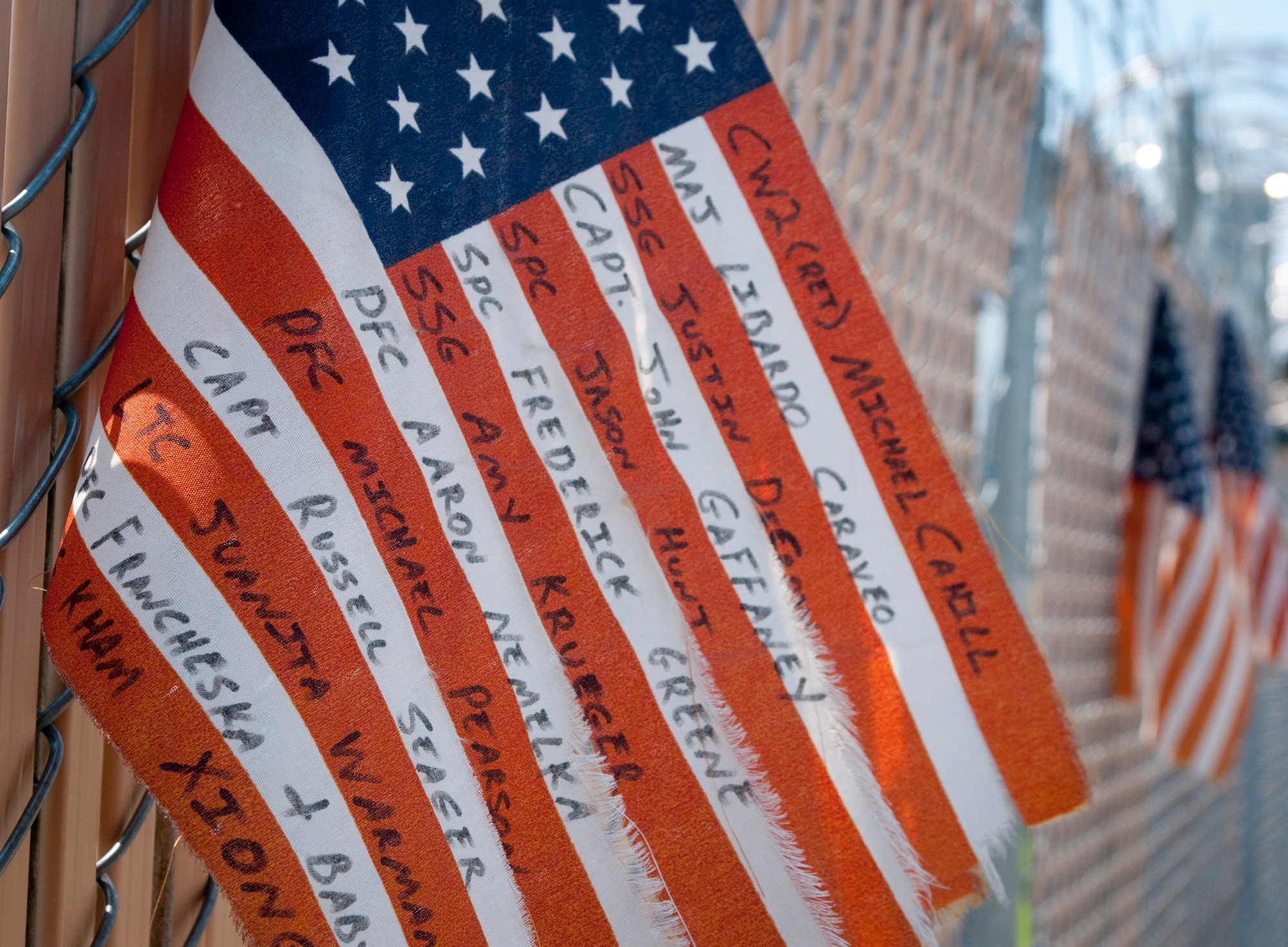 Names of the people killed in the 2009 Fort Hood shooting are handwritten along the stripes of an American flag attached to a memorial fence in 2013.